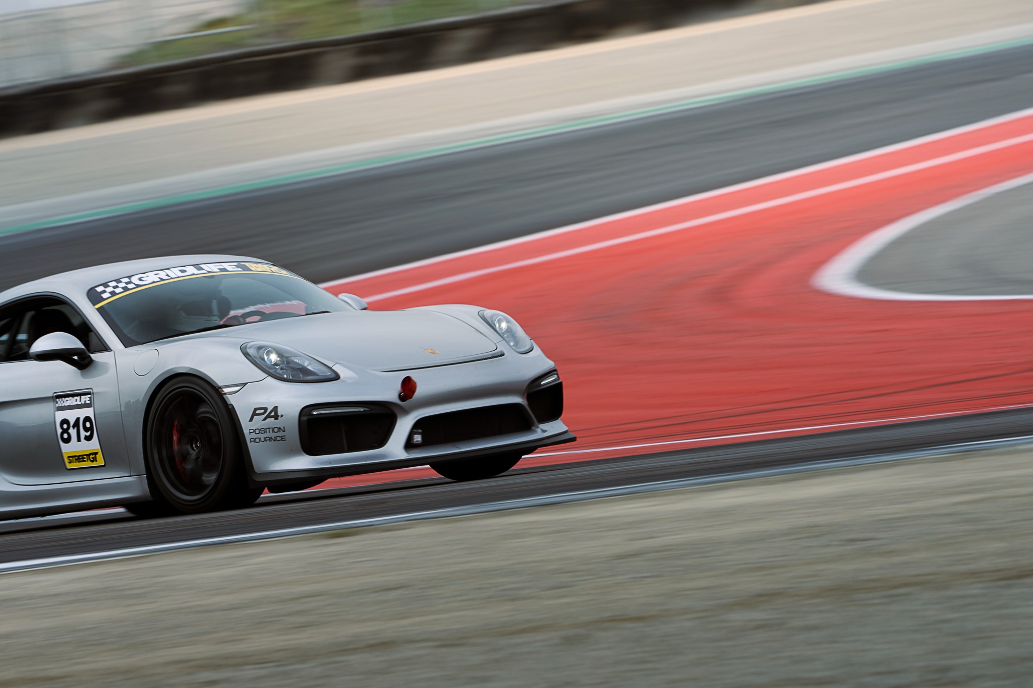 A silver sports car corners at Laguna Seca during GRIDLIFE.