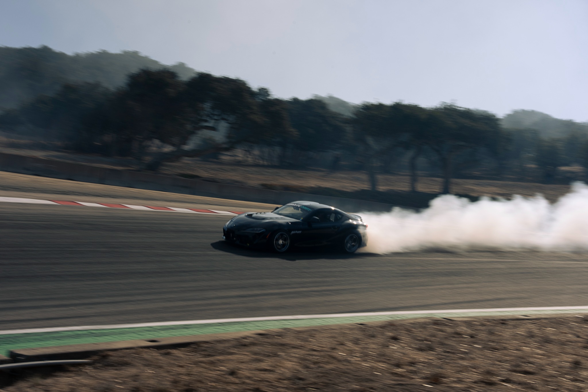 A drift car trails tire smoke across Laguna Seca.