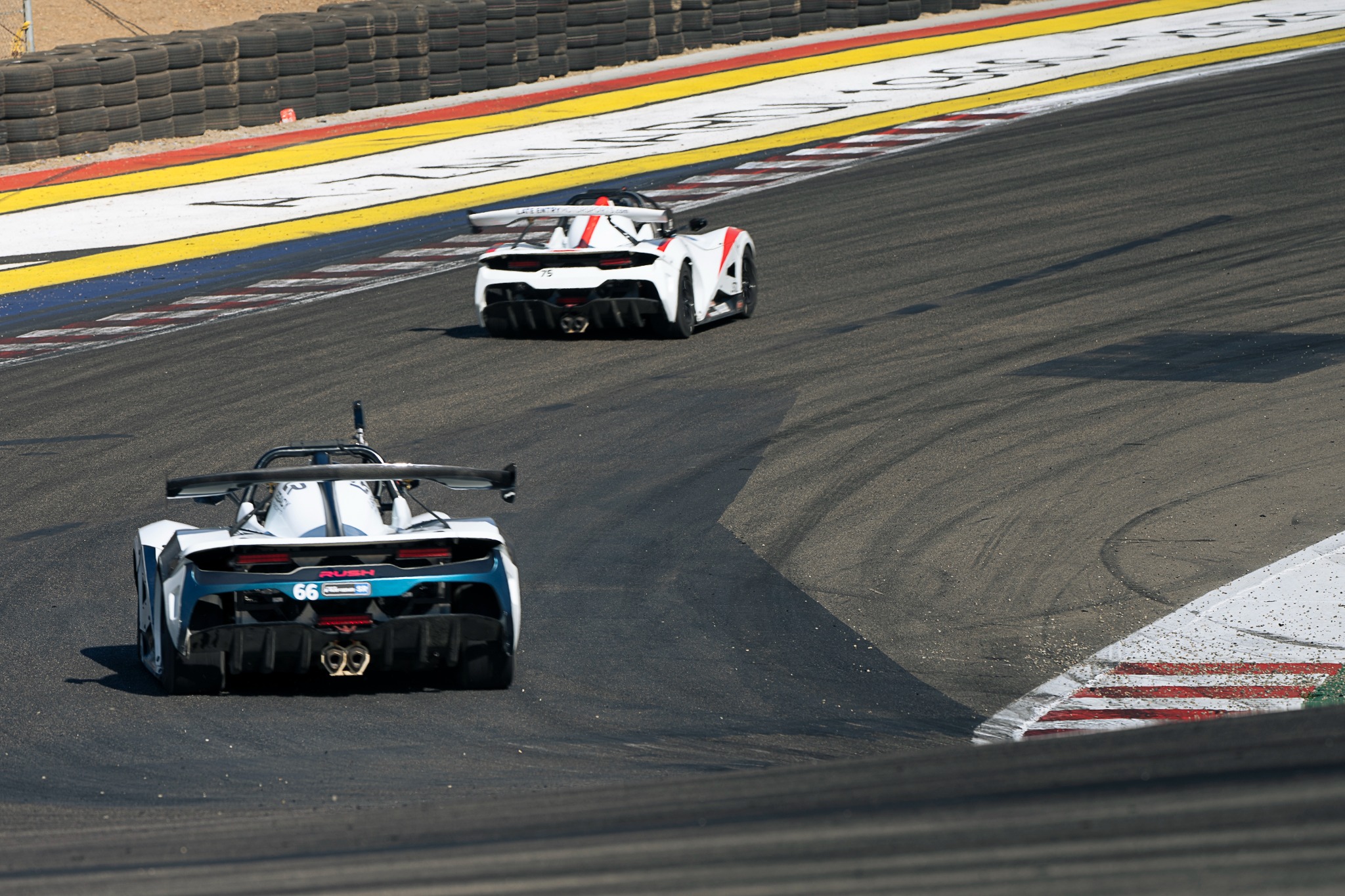 Two prototype race cars climb a section of Laguna Seca.