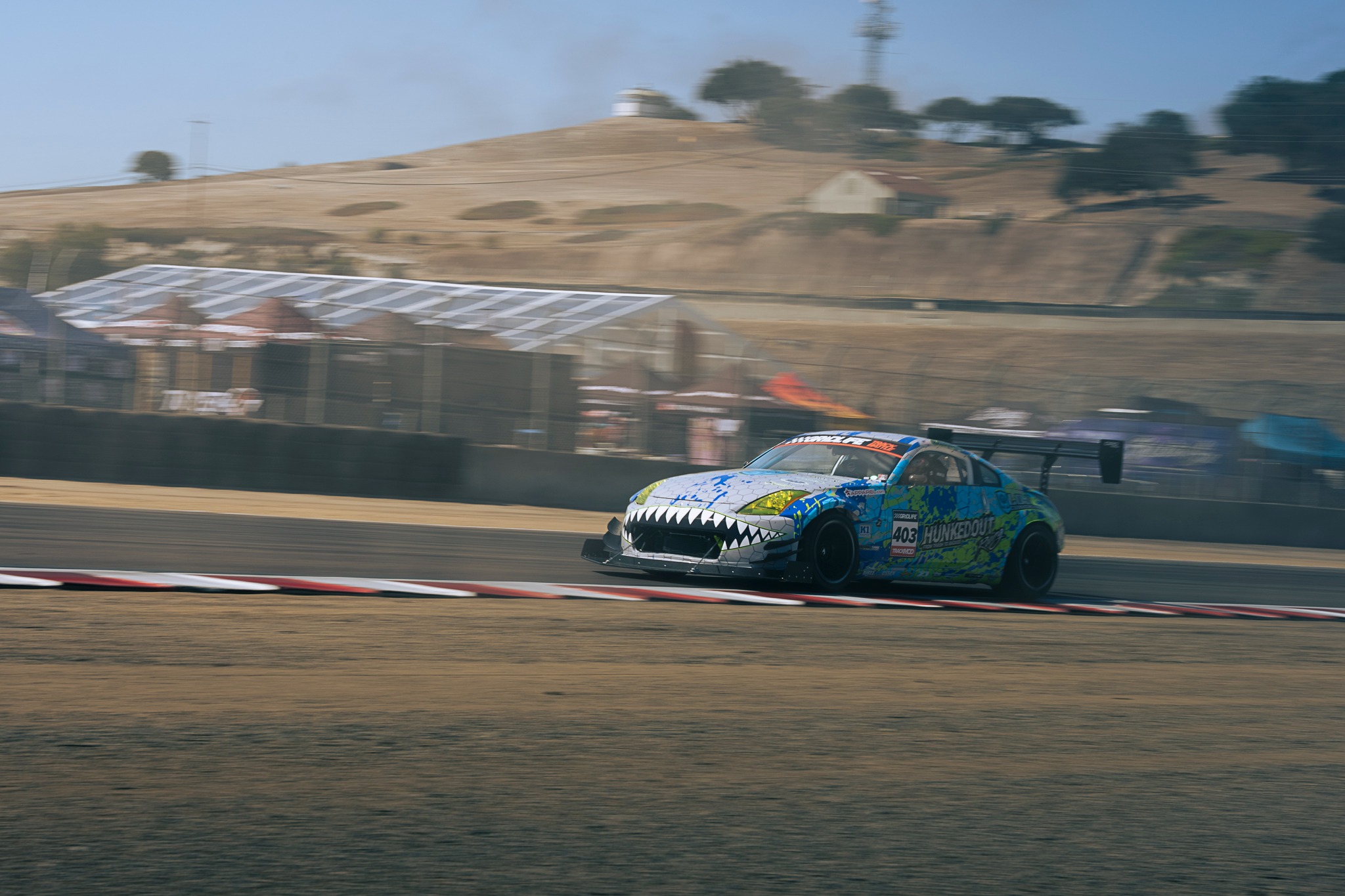A colorful race car passes the Laguna Seca grandstands.