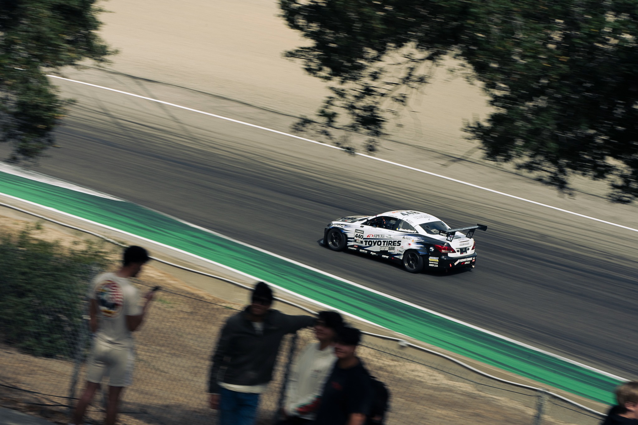 Spectators watch two cars on track at Laguna Seca.